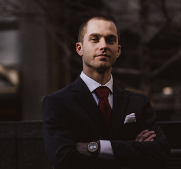Man in a suit with arms crossed against a blurred background